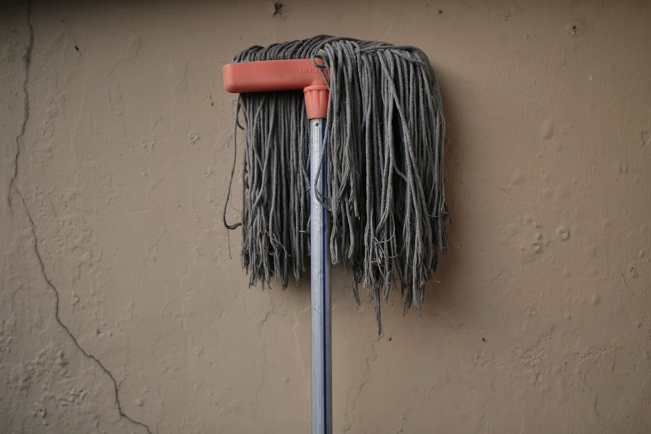 services-04 Gray mop leaning against a textured wall, conveying simplicity in a domestic setting.